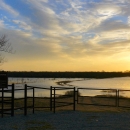 An observation deck looks out onto a body of water during a sunset.