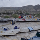 A campsite containing camping and scientific monitoring equipment is shown next to a river containing several canoes.