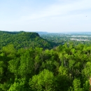Bluff with green foliage with the city of La Crosse in the distance.