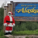 Watercraft inspector, Steve Wogtech, posed in Santa suit in front of Welcome to Alaska sign.