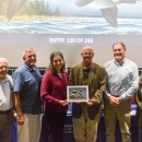 Six judges at the 2025 Federal Duck Stamp Art Contest hold the winning artwork.