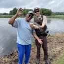 Law Enforcement Officer Mike McMenamin poses with a veteran and the bass he caught at the Veterans' Fishing Derby at Wallkill River National Wildlife Refuge