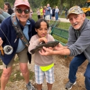 Child posing with volunteers holding fish