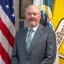 man in suit in front of US, FWS flags