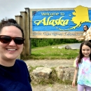 a family stands in front of an alaska sign