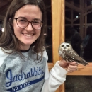 Photo of Alex smiling and holding an owl in her hand.