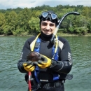 Photo of Andy Roberts in a wetsuit and dive gear holding a freshwater mussel by USFWS.