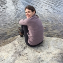 Person sitting on a rock next to water