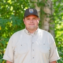 Service staff member, Clint Cole, in uniform with trees in the background