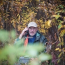 man sitting in woods talking on a radio