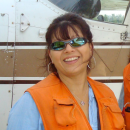 Woman in orange vest stands in front of a float plane door