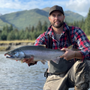 Man in plaid shirt holds a salmon in his hands