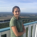 a white woman with brown hair stands at a scenic overlook