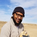 Man wearing beanie holds a black tailed prairie dog 
