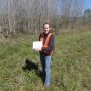 Erin Padgett holding a clipboard doing field work.