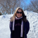 A portrait of Janet Lebson standing in front of a snow pile
