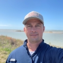 A man taking a selfie outside along the shoreline 