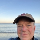 man in hat stands on frozen lake