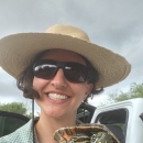Photo selfie of a woman in a hat and sunglasses holding a turtle