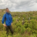 Miguel standing in a field in a blue jacket and smiling