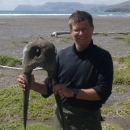 Man holding walrus skull by the tusks on the Alaska tundra