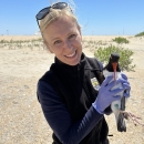 A blond woman holds an American oystercatcher in gloved hands