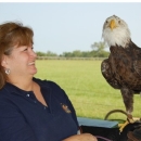 Reese smiles at a bald eagle beside her. She is wearing a navy blue FWS uniform polo