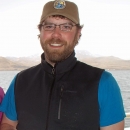 Man in brown hat and black vest with blue shirt .