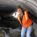 Bill stands in water at the entrance to a large culvert
