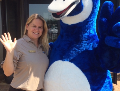 woman in FWS uniform smiles next to blue goose mascot