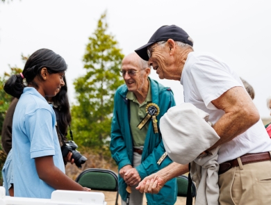 A young girl talks with a group of adults at an outdoor event