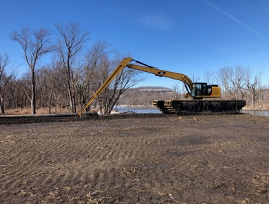 An excavator is moving dirt on an island of the river
