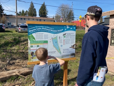 An adult and child read a sign at Wapato Lake National Wildlife Refuge.