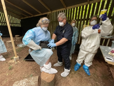 A group of scientists in personal protective gear hold a vulture while preparing to vaccinate the animal.