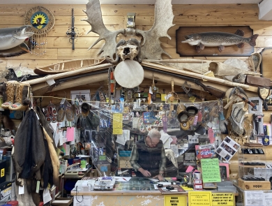 person working in an office with pelts and antlers and outdoor items all around