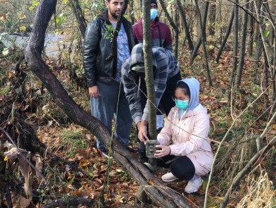students setting up trail camera in the woods