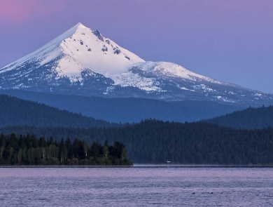 a body of water with a snow covered mountain in the background