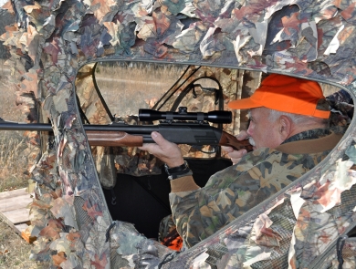 A hunter takes aim at a deer from a blind