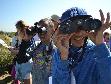 Smiling youngsters use binoculars to look at birds at San Diego Bay National Wildlife Refuge.