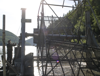 man standing on a fish wheel platform in a large river