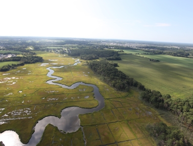 Green marshland, a wandering river and human-made canals are visible in this aerial of Cape May National Wildlife Refuge.