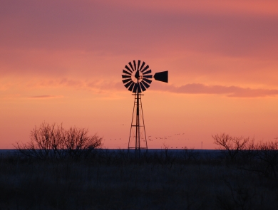 A windmill on the prairie at sunset