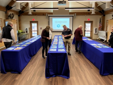 Judges reviewing artwork laid out on tables. 