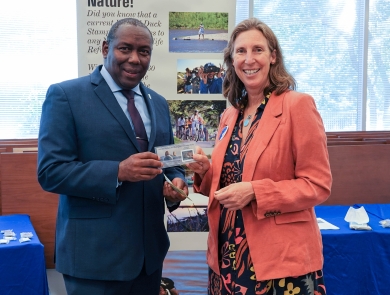 Assistant Director for Migratory Birds, Jerome Ford, stands with Director Martha Williams as they hold the newly issued duck stamp.