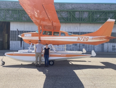 2 people stand in front of a survey aircraft