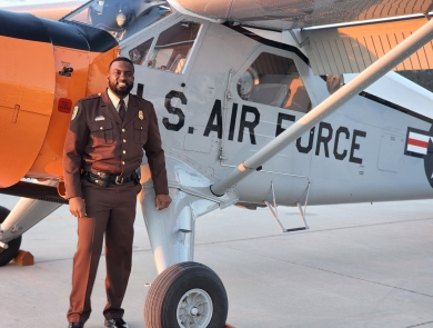 African American man stands in front of plane with "U.S.  AIR FORCE" on side