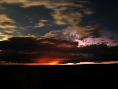 Sunset, stars, and storm clouds converge over a silhouetted landscape