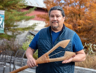up close image of man holding wooden spear with fall leaves in background