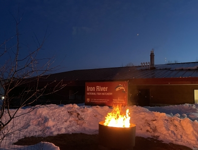 a fire in a fire ring in front of Iron River NFH sign