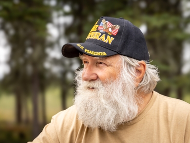 Man with a beard wearing a Marine veteran hat